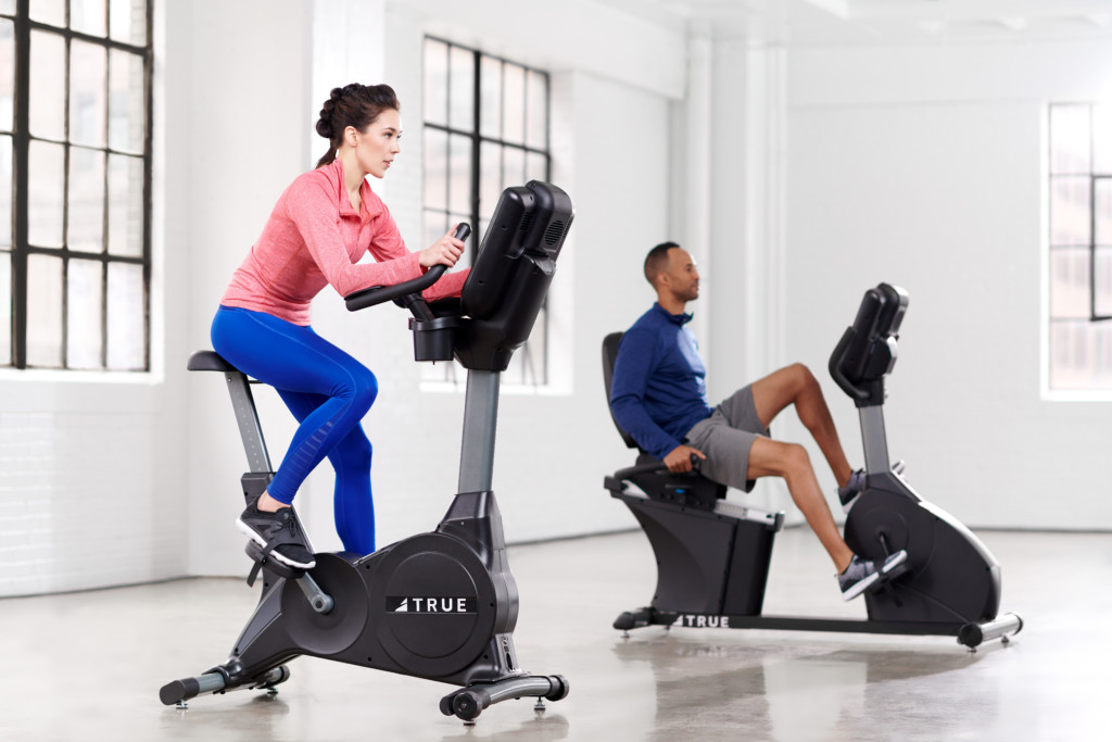 man and woman working out on bikes in gym