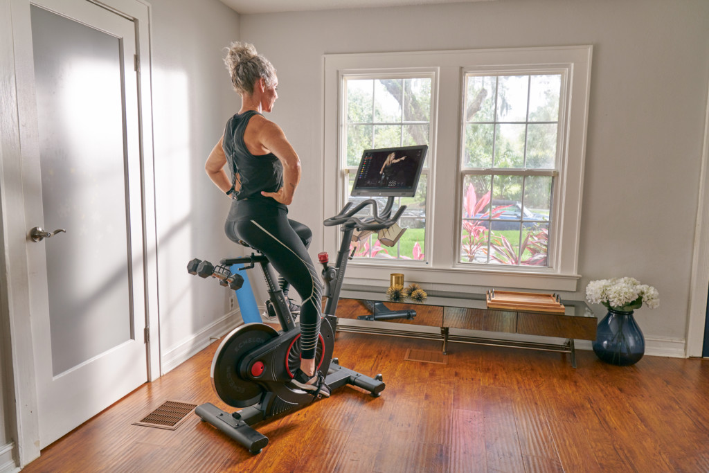 woman using stationary bike to workout in her home gym