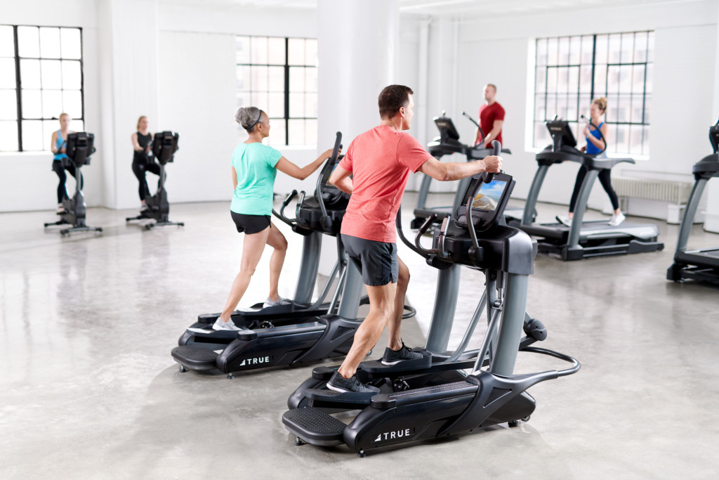 man and woman working out on ellipticals in commercial gym