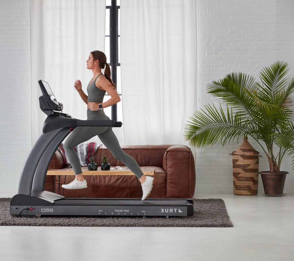 woman running on treadmill placed in front of her couch